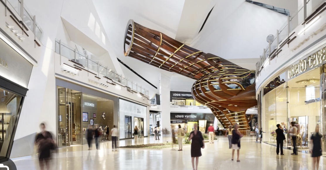 A modern luxury shopping mall with a sculptural wooden installation